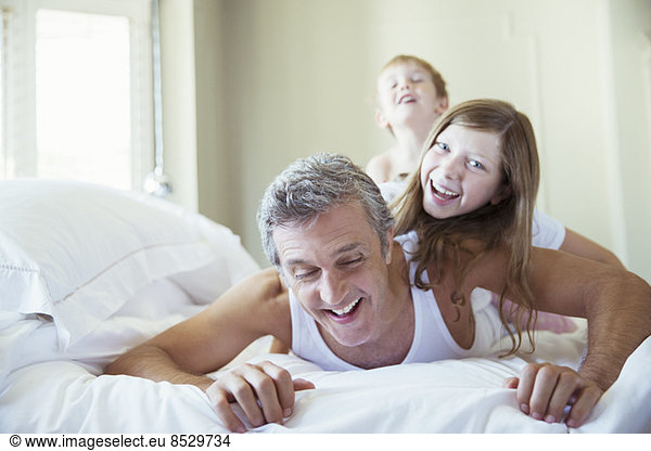 Father and children playing on bed