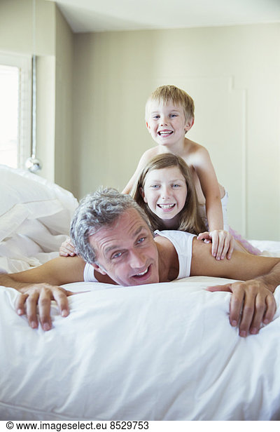 Father and children playing on bed