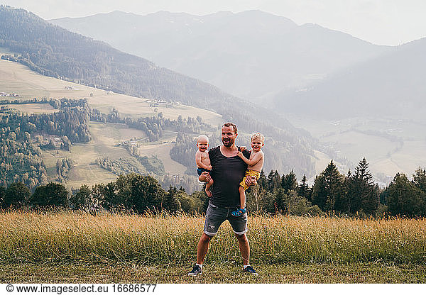 Father and children smiling at the camera in the alps during holidays