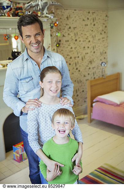 Father and children smiling in bedroom