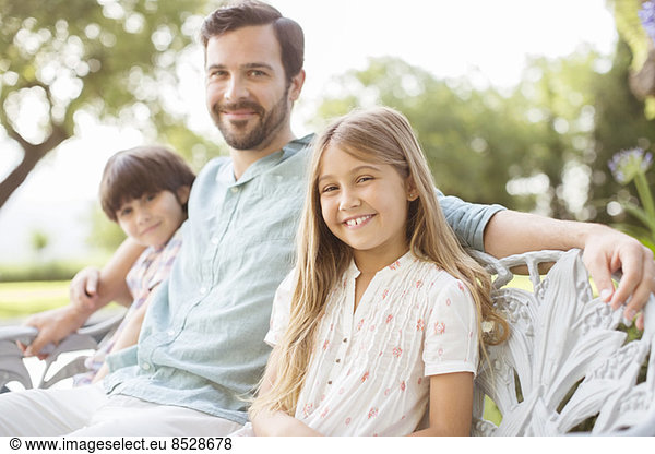 Father and children smiling on bench