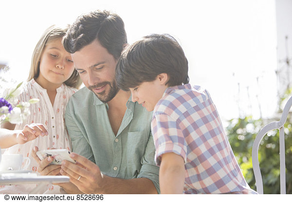 Father and children using cell phone outdoors