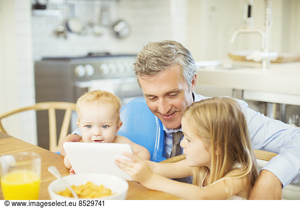 Father and children using digital tablet at table