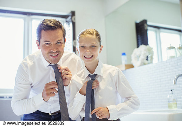 Father and daughter adjusting ties in bathroom