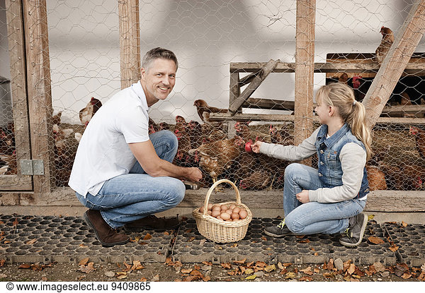 Father and daughter at henhouse on organic farm