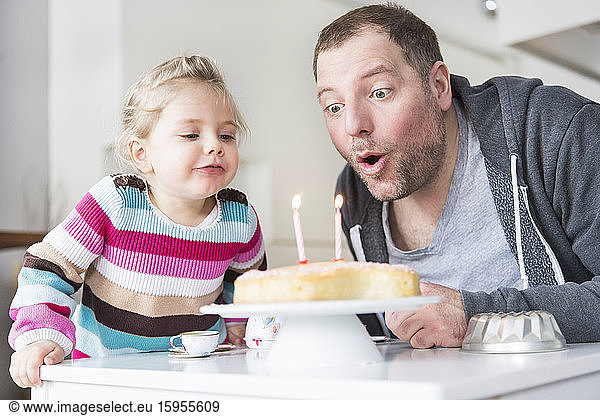 Father and daughter blowing out birthday candles