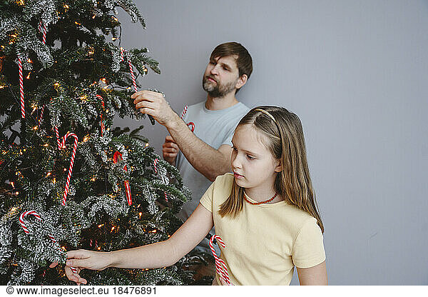 Father and daughter decorating Christmas tree at home