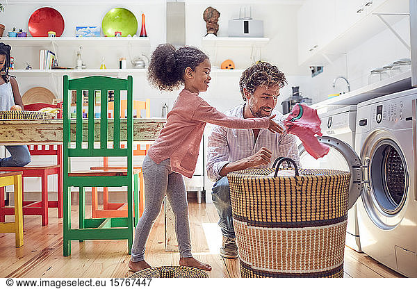 Father and daughter doing laundry in kitchen