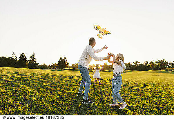 Father and daughter flying kite together in park