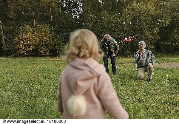Father and daughter flying model airplane on grass