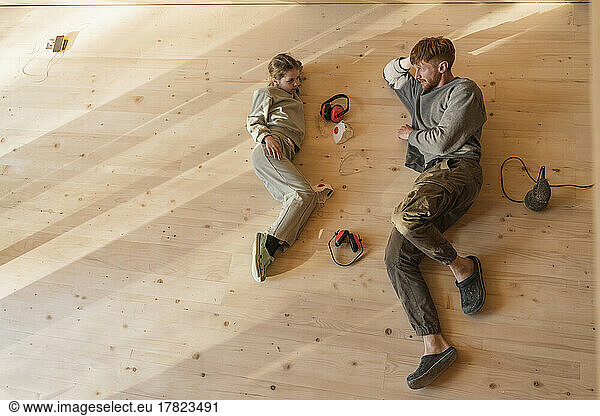 Father and daughter have rest  lying after sanding the floor in an eco house. Top view  time together