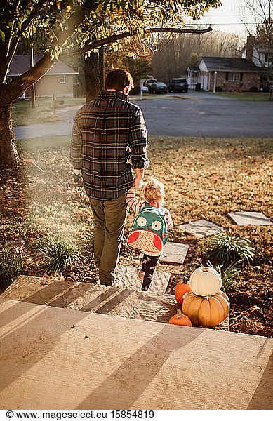 Father and daughter holding hands walking off porch