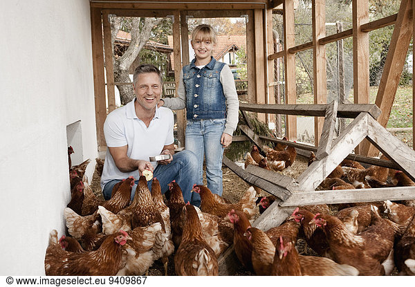Father and daughter in henhouse on organic farm