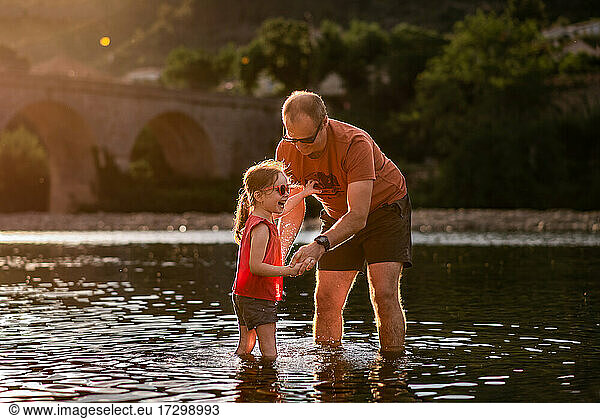 Father and daughter play in river in France in summer