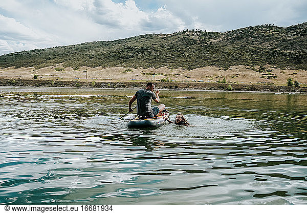 Father and daughter playing with a paddle board on a lake