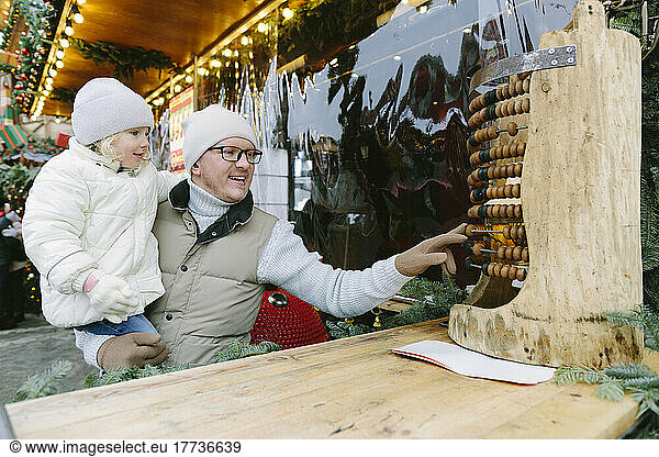 Father and daughter playing with abacus at Christmas market