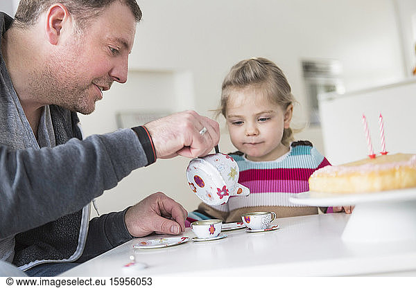 Father and daughter playing with doll's china set