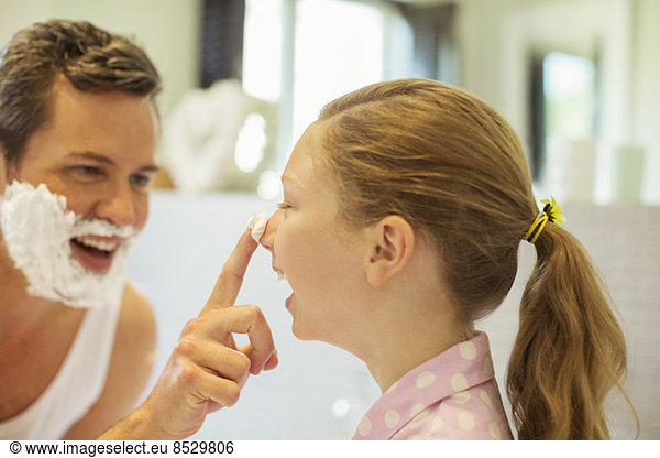 Father and daughter playing with shaving cream in bathroom