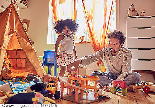 Father and daughter playing with toys on floor