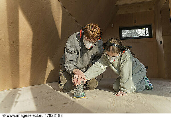Father and daughter sanding the floor in their new eco house