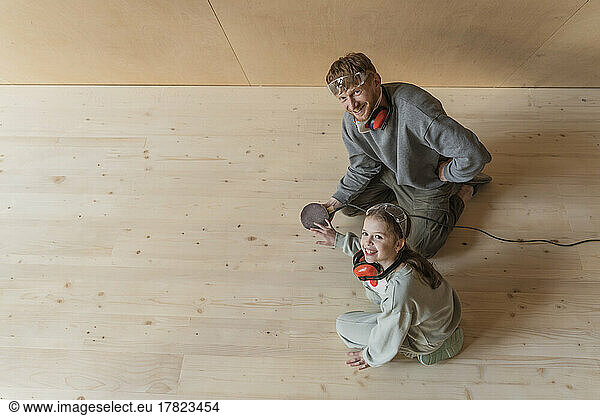 Father and daughter sanding the floor in their new eco house