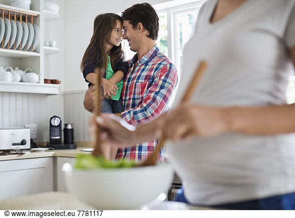 Father and daughter touching noses in kitchen