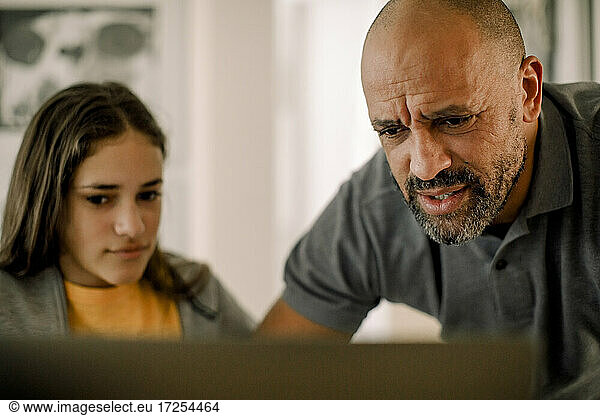 Father and daughter using laptop in kitchen