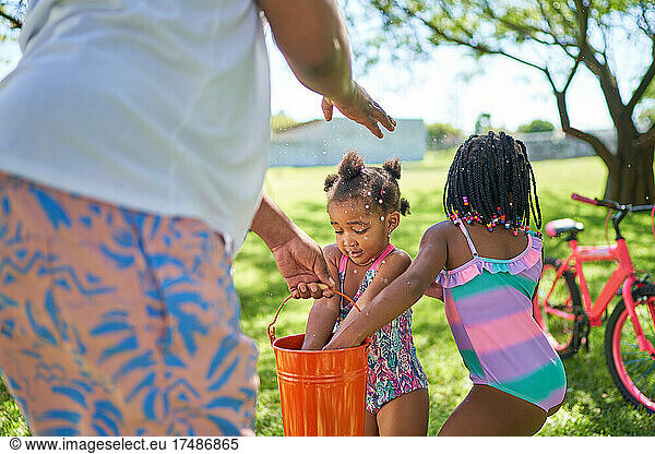 Father and daughters splashing water in summer backyard
