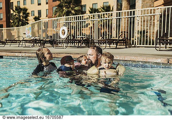 Father and four children playing in pool together in Palm Springs