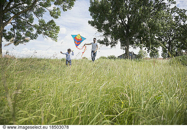 Father and his son running with kite in the countryside  Bavaria  Germany