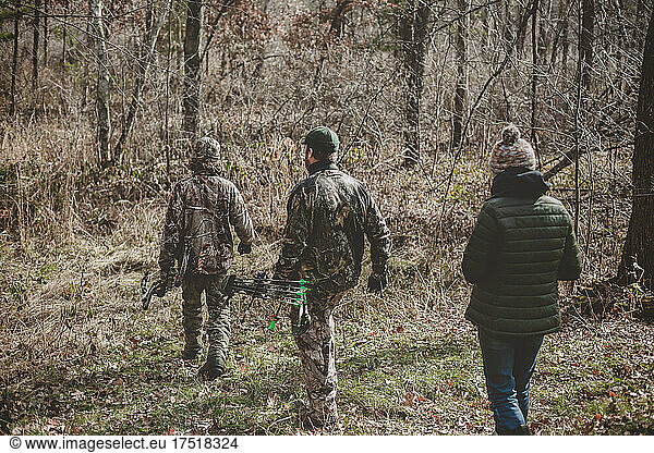 Father and his two teens walking into woods to track deer