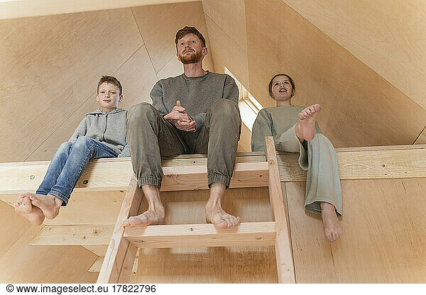 Father and kids sitting on the second floor ladder in eco house