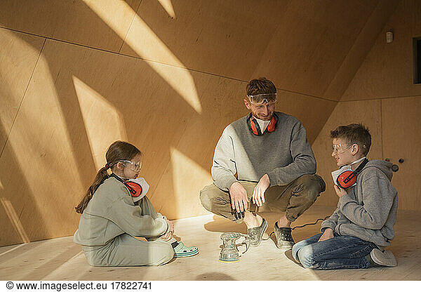 Father and kids working together  sanding the floor in their eco house