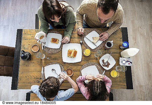 Father and mother having breakfast with children at home