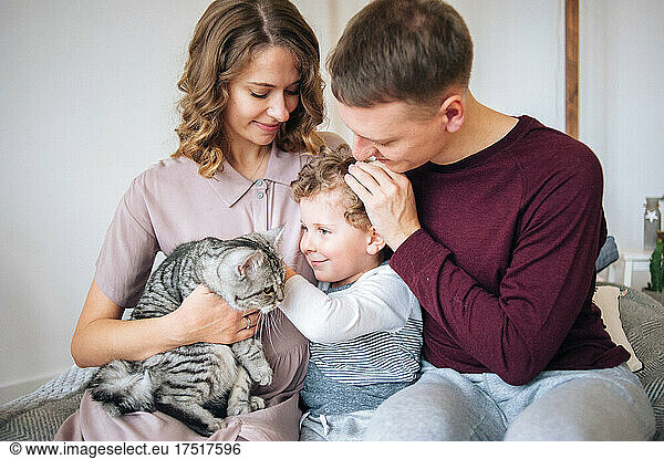 Father and mother hold their son and cat on hands. Tender moment