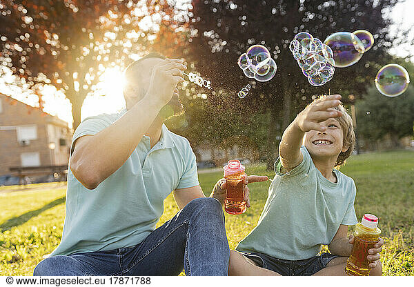 Father and son blowing bubbles at park