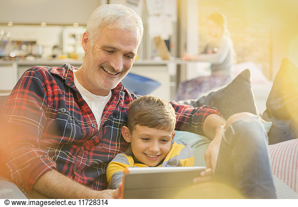Father and son bonding  sharing digital tablet on sofa