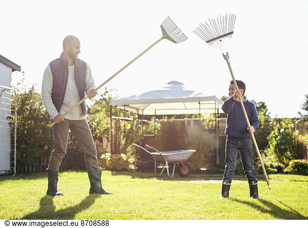 Father and son fighting with rakes at yard