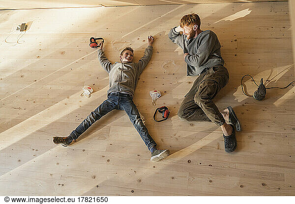 Father and son have rest  lying after sanding the floor in an eco house. Top view  time together
