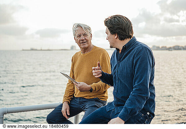 Father and son having discussion sitting in front of sea