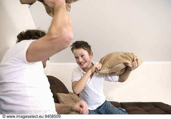 Father and son having pillow fight in living room