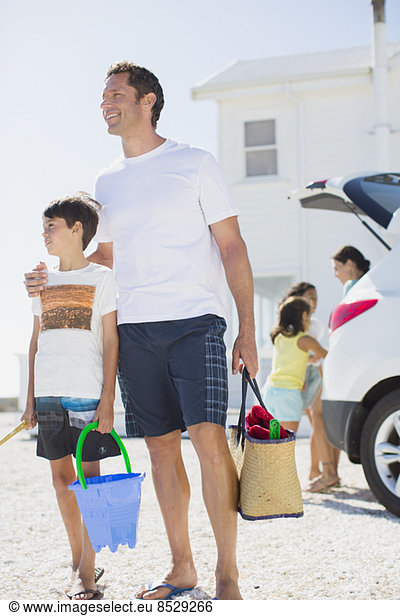 Father and son holding beach gear by car