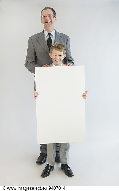 Father and son holding blank whiteboard  smiling  portrait
