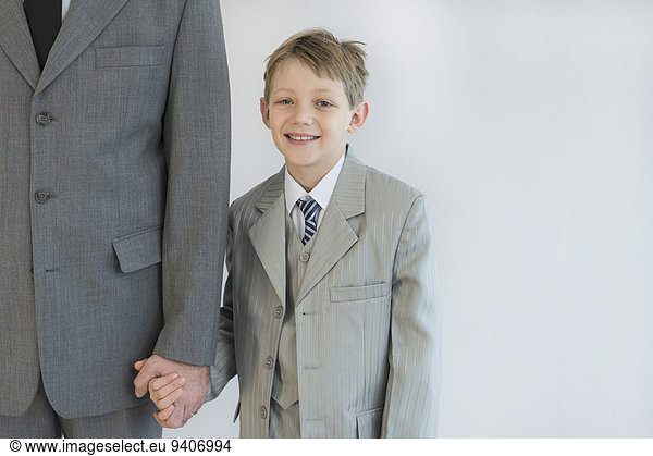 Father and son holding hands against white background