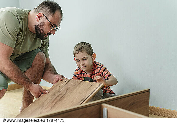 Father and son installing furniture at home
