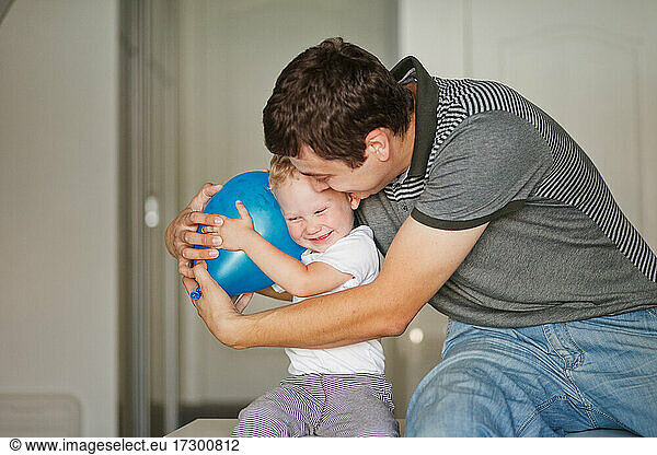 father and son laugh and hug with blue balloon
