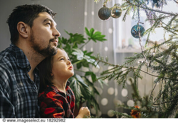Father and son looking at decorated Christmas tree