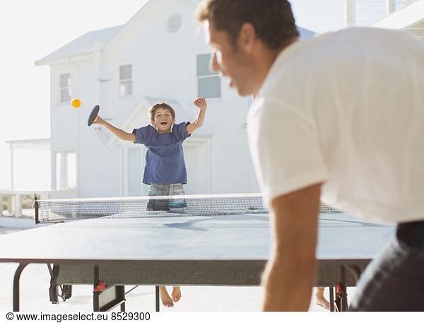 Father and son playing table tennis outdoors