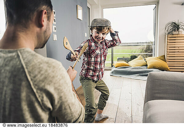 Father and son playing with spatulas at home