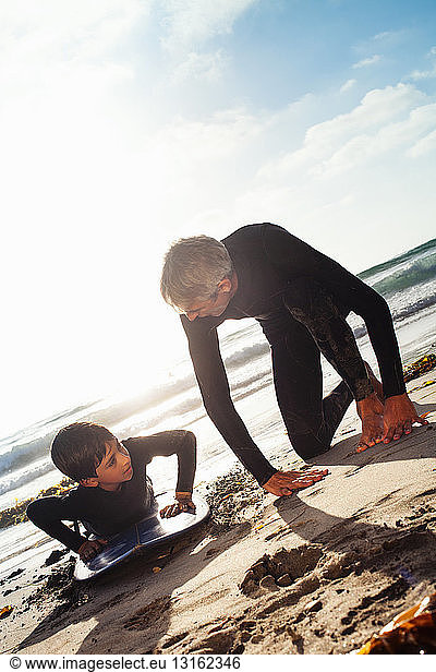 Father and son practicing on surfboard at beach  Encinitas  California  USA